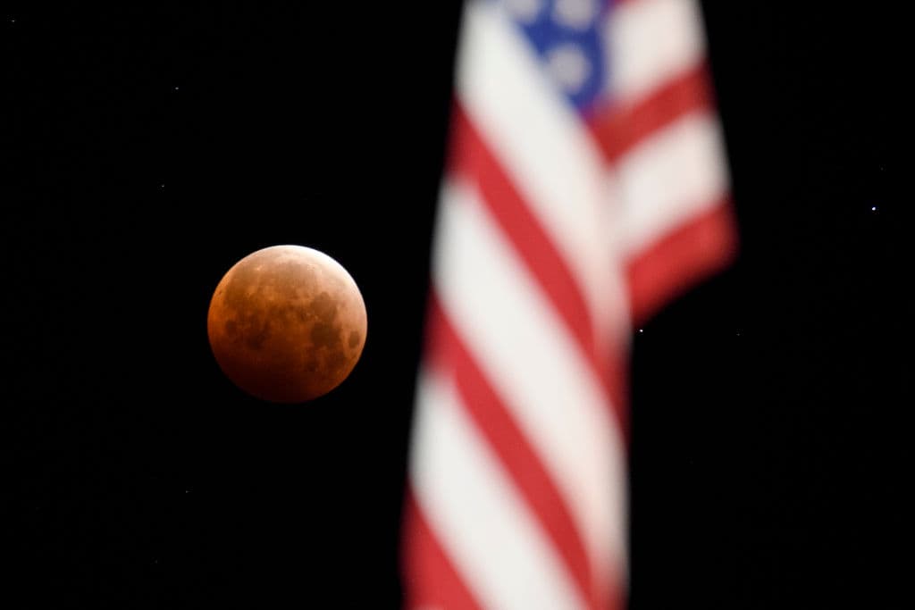 La superluna enmarcada con una bandera de Estados Unidos durante el eclipse lunar total en Chico, California.
