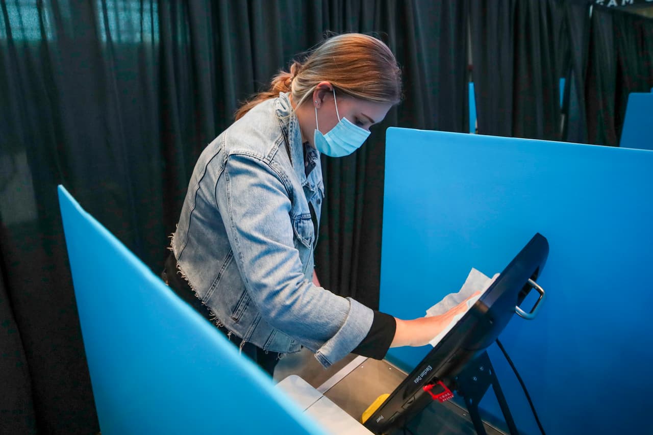 Meghan Pollock limpia la mesa de votación durante el día de las elecciones en el United Center en Chicago, Illinois, durante las elecciones generales del 3 de noviembre. Las medidas sanitarias han sido parte del proceso electoral en medio de la pandemia.