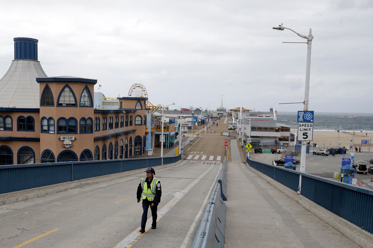 Un oficial de policía camina por el muelle de Santa Mónica, California, cerrado temporalmente. El plan económico que propondrá el gobierno al Senado solicitará $100,000 millones para apoyar a trabajadores.