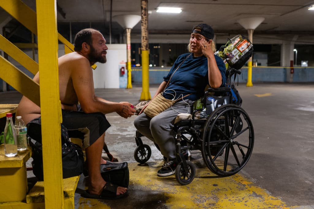 Dos personas sin hogar buscan refugio antes de la llegada del huracán Milton.