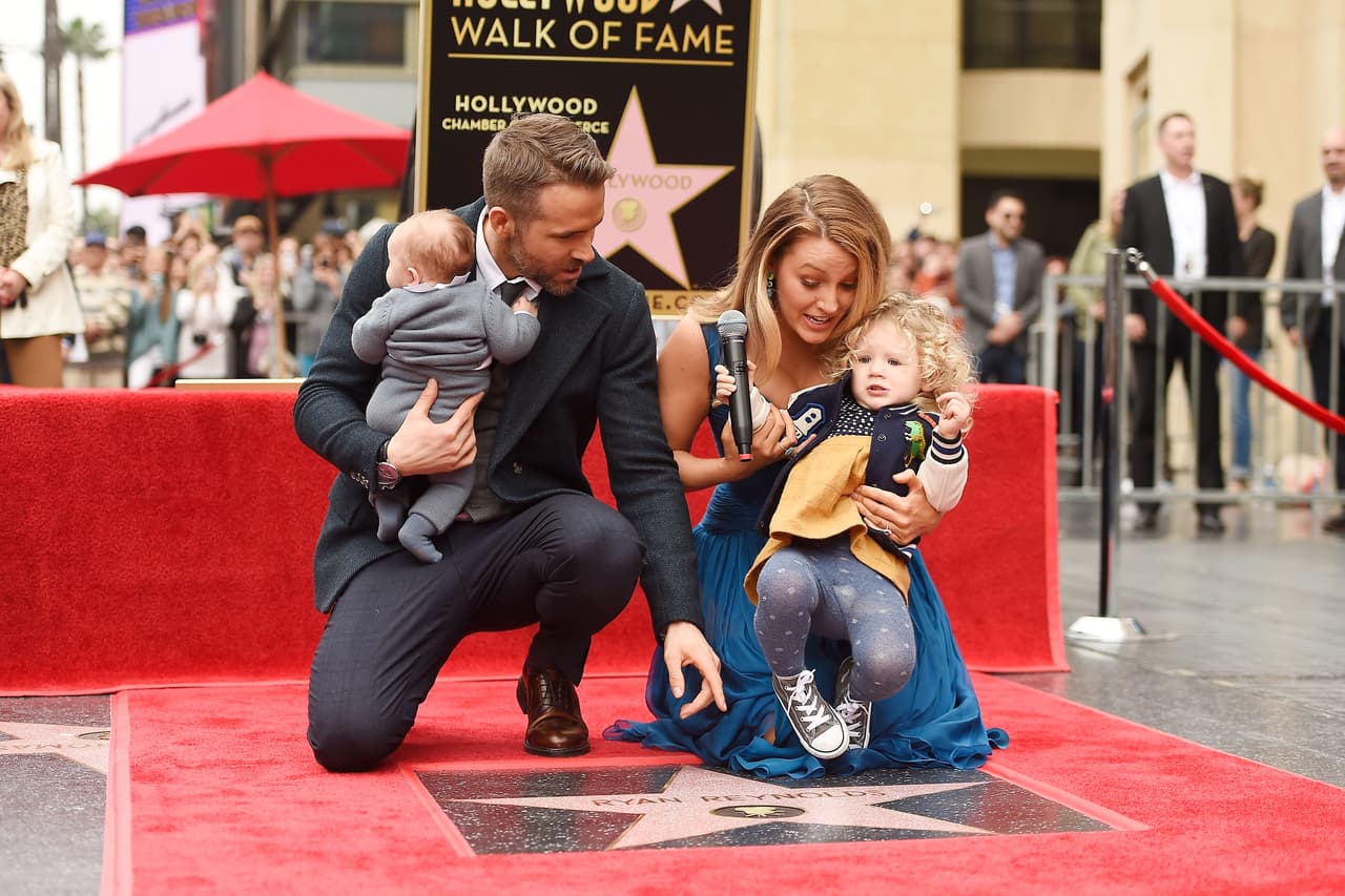 Ryan Reynolds intentando llamar la atención de su hija mayor, James, mientras carga a su pequeña de sólo dos meses.