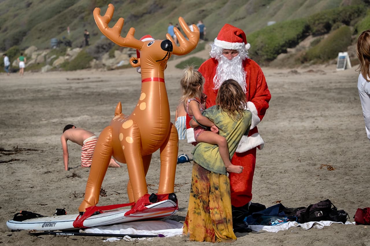 Mike Mitrowski, vestido de Papá Noel, saluda a los niños antes de participar en el evento Surfing Santa en Dana Point.