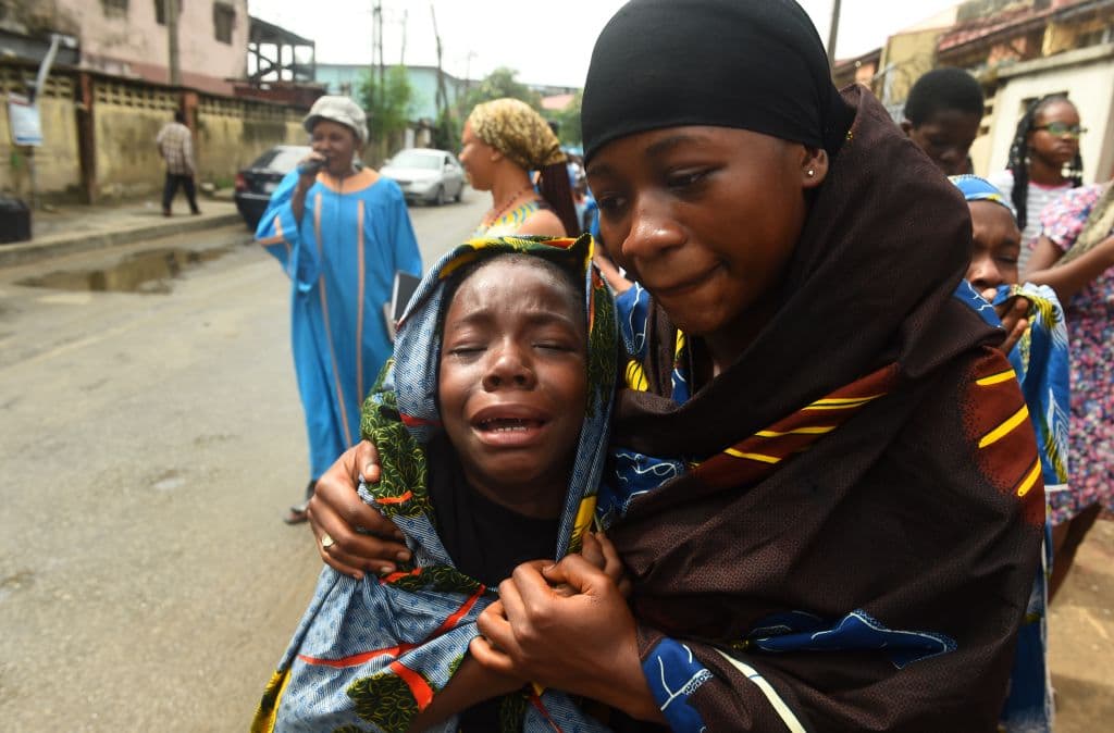 Madre e hija religiosas lloran durante la procesión de Viernes Santo en Nigeria.