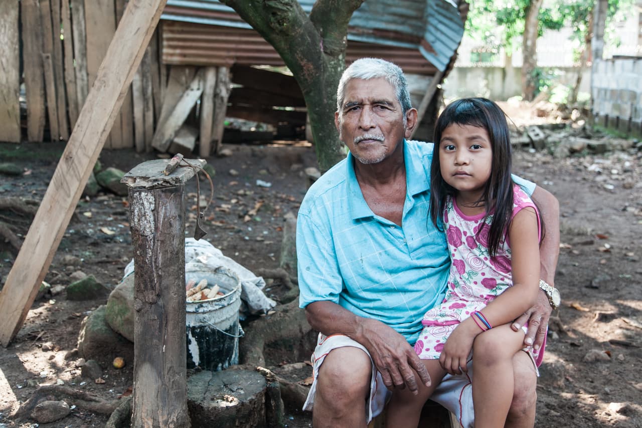 Adayanci posa con su abuelo delante de su casa en Santa Ana. Por sus bajos recursos de la familia y por vivir en un lugar alejado de la capital, a los Pérez Chávez les resulta casi imposible tener acceso a un tratamiento psicológico y terapia.