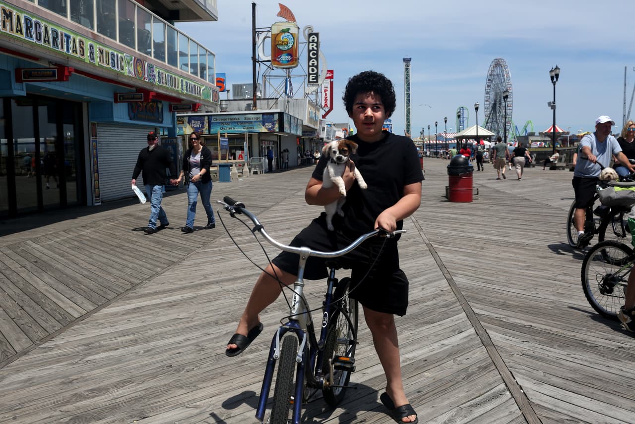 Un joven se pasea con su perro en un malecón de Jersey Shore.