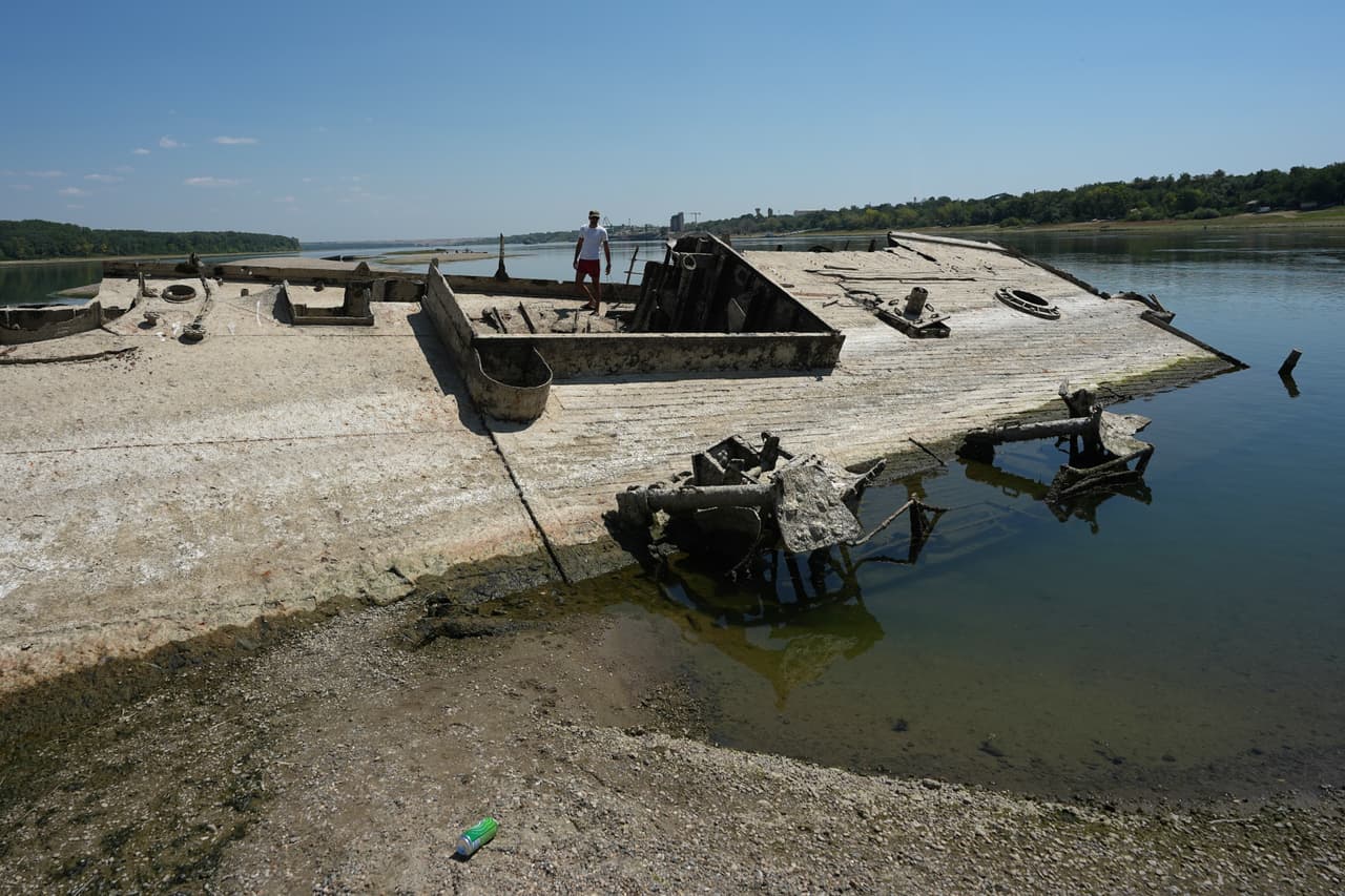 Un hombre camina sobre los restos de un buque de la Alemania nazi que emerge del fondo el río Danubio gracias a la sequía.