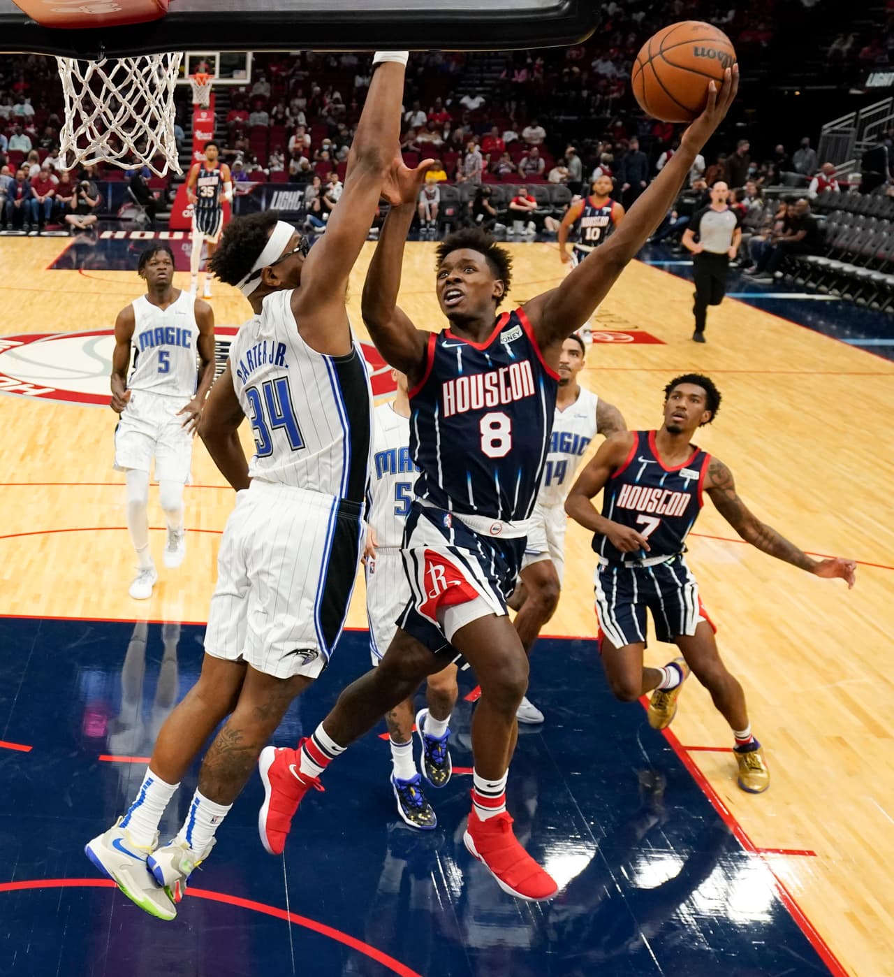 Jae'Sean (8) Tate de los Rockets de Houston lanza hacia el aro frente a la defensiva de Wendell Carter Jr. (34), de los Magic de Orlando.