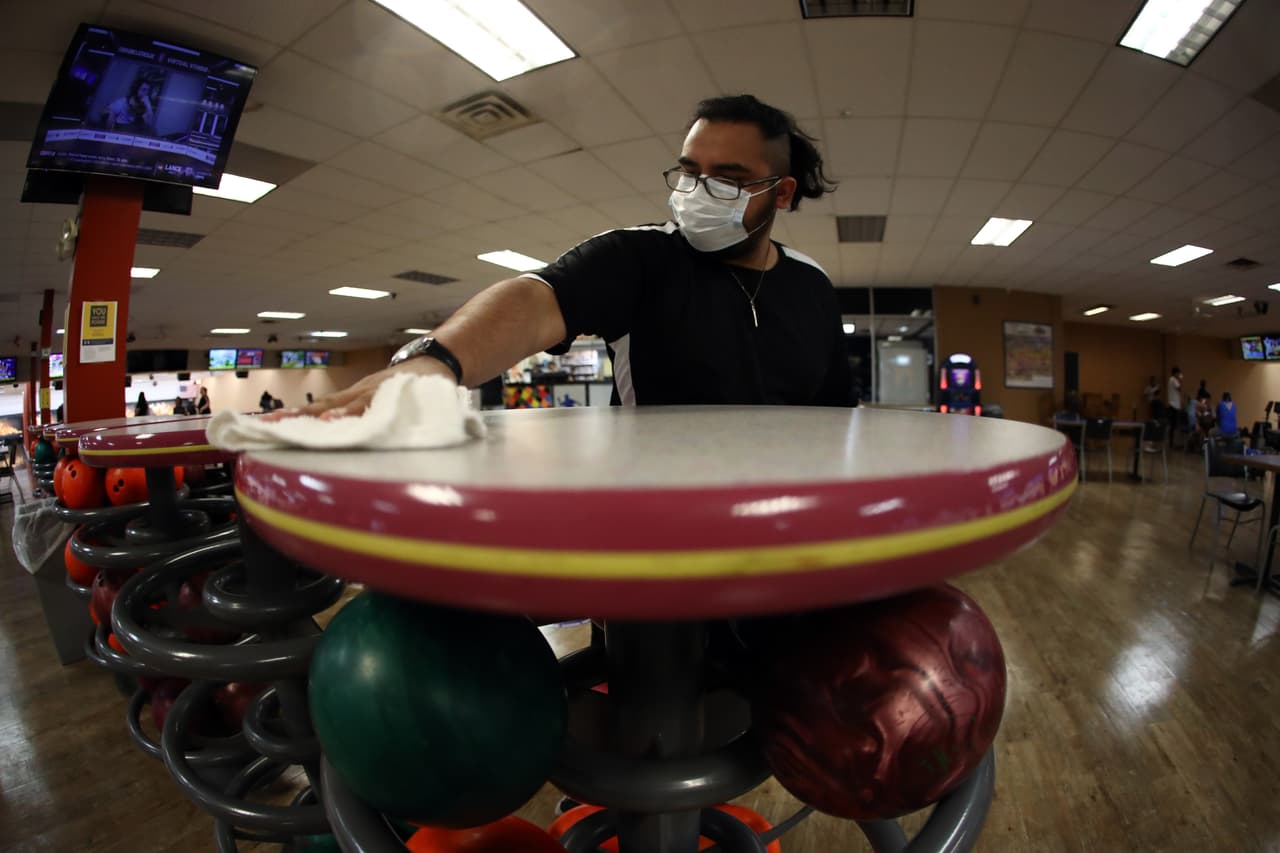 Michael Garcia, trabajador del Cowtown Bowling Palace, limpia una mesa el 22 de mayo de 2020 en Fort Worth, Texas. El gobernador Abbott ha enfrentado críticas por lo que algunos han llamado “señales contradictorias”.