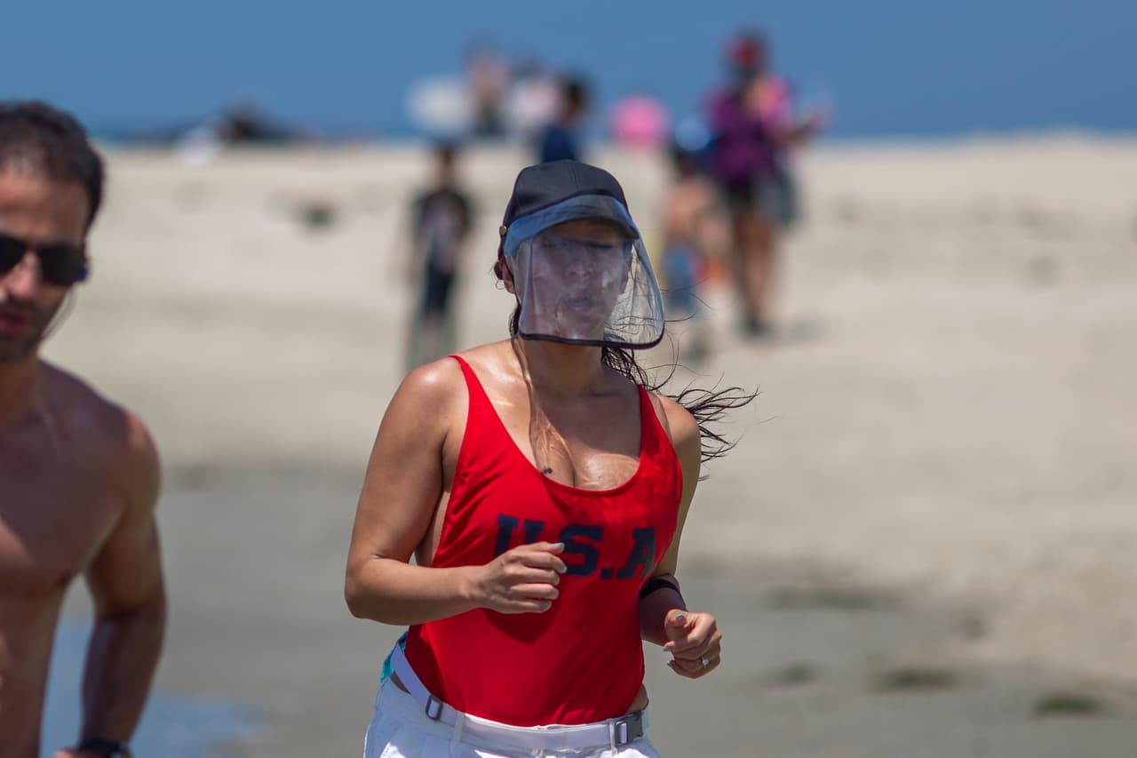 Esta mujer salió a ejercitarse en la playa de California llevando una pantalla protectora transparente en la cara. Muchas playas del sur del estado estaban abiertas sólo para nadar, correr y realizar otras actividades. Tomar el sol y actividades en grupo como jugar voleibol están prohibidas.