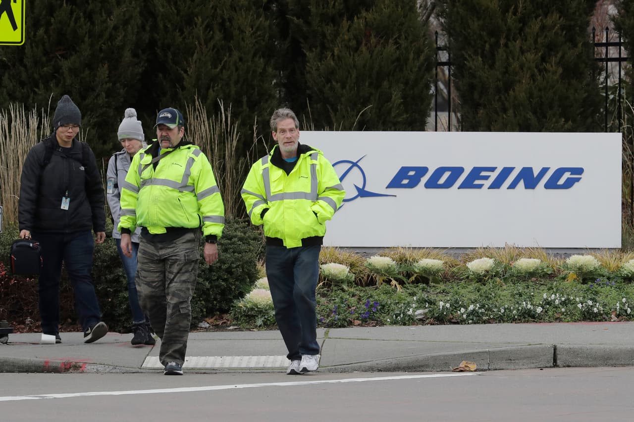 Los trabajadores pasan junto a un cartel de Boeing Co. cuando salen de la fábrica donde se construyen los aviones 737 Max de la compañía, el martes 17 de diciembre de 2019, en Renton, Washington.