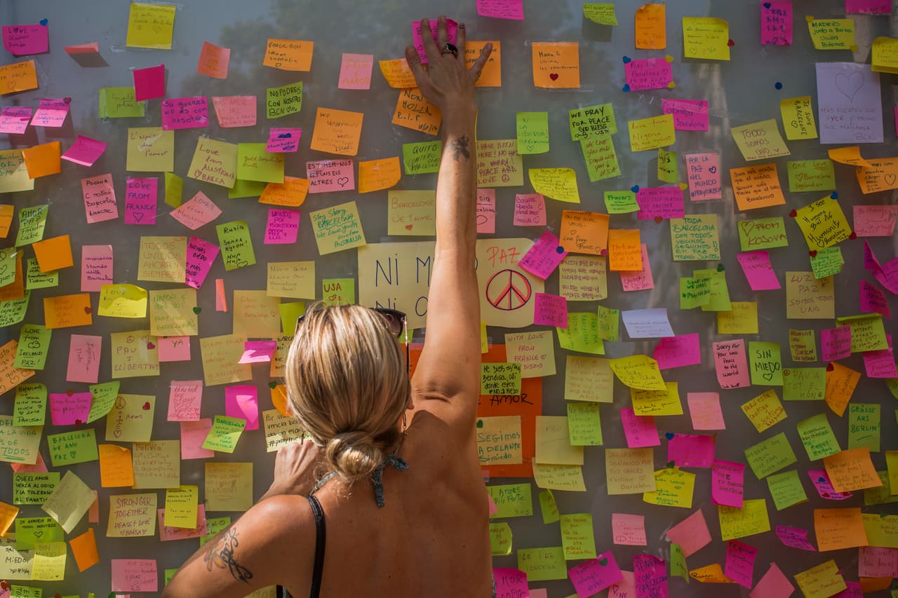 Una mujer deja un mensaje como homenaje a las víctimas en el histórico paseo de la Rambla.