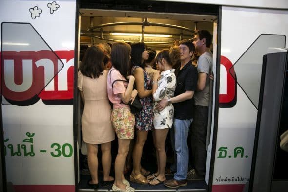 La gente sube como puede a un tren en Bangkok para regresar a casa.