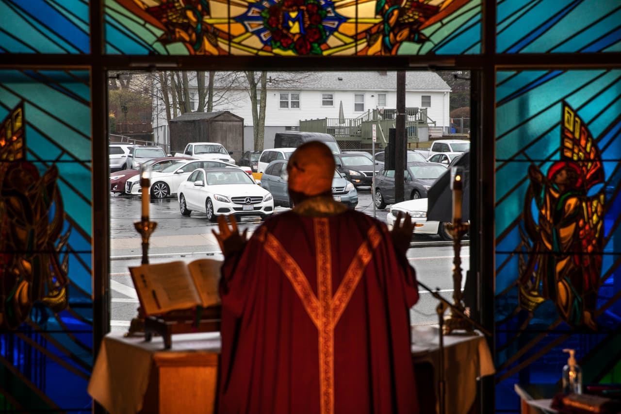 <b>Una misa a distancia. </b>Un sacerdote católico celebra un servicio religioso desde la puerta de su iglesia, que los fieles escuchan a través de una señal de radio en sus autos. Johnston, Rhode Island, 29 de marzo.