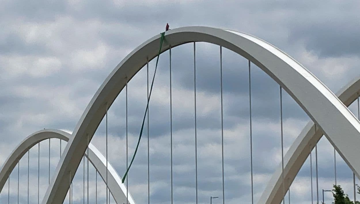 Hombre escala a la cima del Frederick Douglass Memorial Bridge en protesta de May Day contra Trump