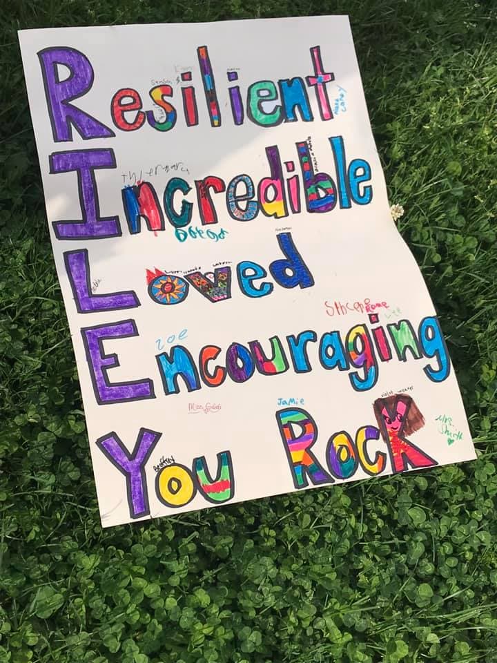 Uno de los regalos que le dio la comunidad a Riley fue un cartel que dice en vertical RILEY, su nombre, y en vertical lo que significa para ellos cada palabra. R: Resilente. I: Increíble. L: Amada. E: Alentadora. Y: You Rock.