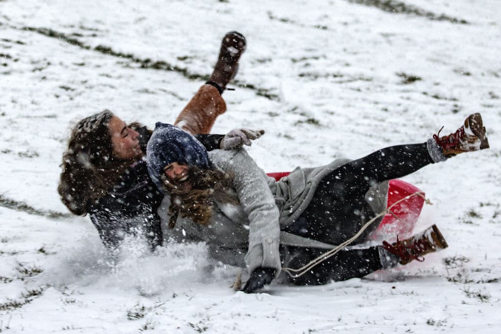 Varias personas juegan en la nieve este domingo. Se prevé que Washington DC reciba una pulgada más de nieve antes de que comience a llover, lo que se espera continúe hasta la próxima semana.