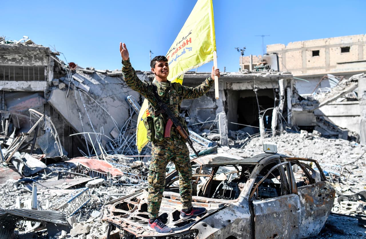 Un miembro de las Fuerzas Democráticas Sirias celebra la reconquista de Raqqa en la icónica plaza Al-Naim, destrozada y llena de escombros. La alianza antiyihadista apoyada por Estados Unidos afirmó el martes 17 de octubre haber retomado el "control total" de la ciudad tras más de cuatro meses de combates con Estado Islámico.