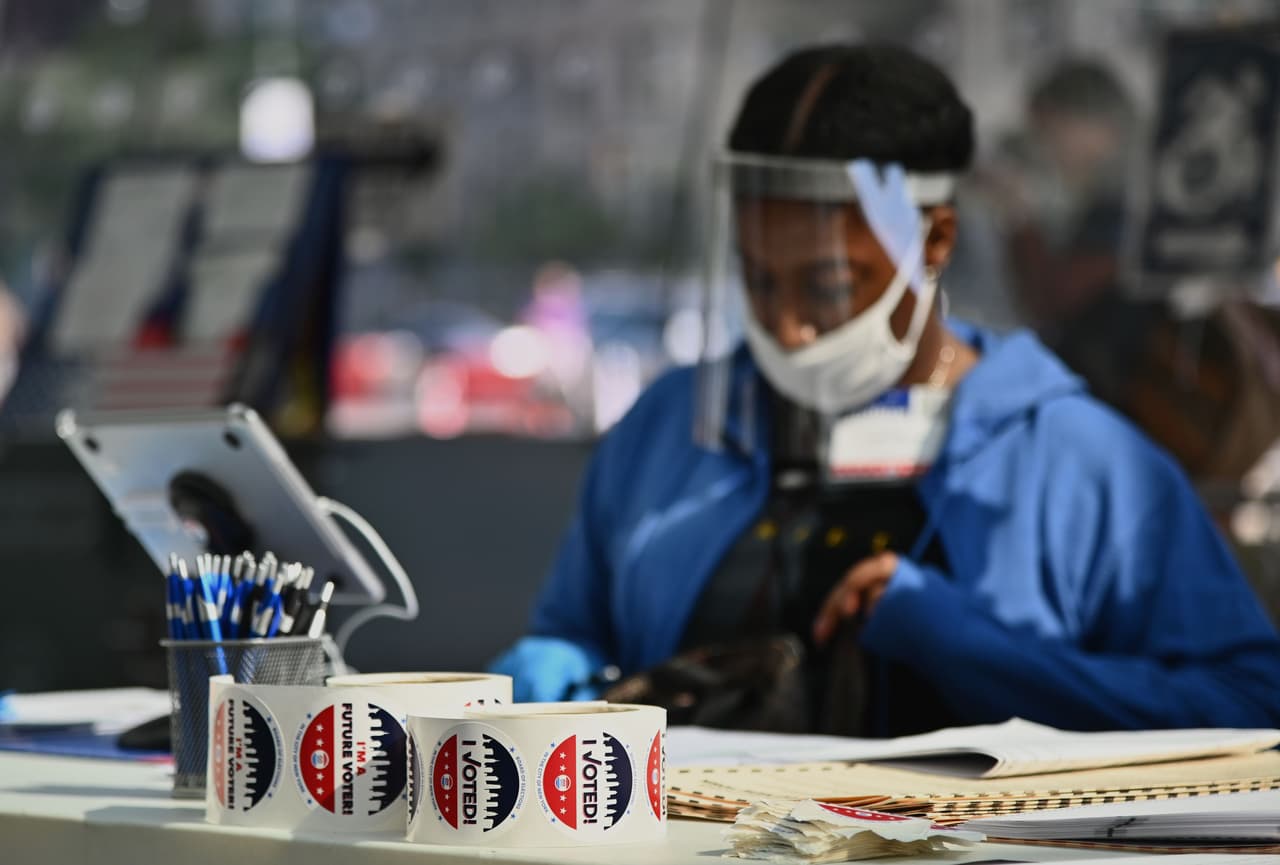 Un empleado de la Junta Electoral que usa equipo de protección personal en una de las mesas del centro de votación ubicado en el Museo de Brooklyn. Nueva York celebra sus elecciones primarias presidenciales demócratas este martes en medio de la pandemia.
<br>