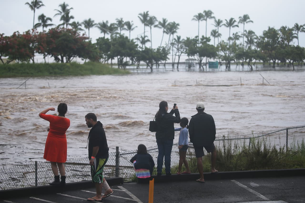 Residentes de Hila observan y toman fotografías de una zona inundada tras las fuertes lluvias de este jueves a causa del huracán Lane.