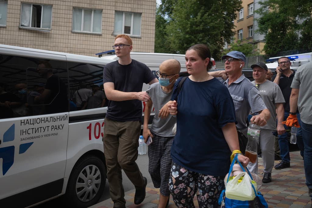 People help to evacuate a boy who suffers from oncology, after Russian missile hit the country's main children hospital Okhmadit in Kyiv, Ukraine, Monday, July 8, 2024. The sign on the ambulance vehicle reads "National Institute of Cancer". (AP Photo/Efrem Lukatsky)