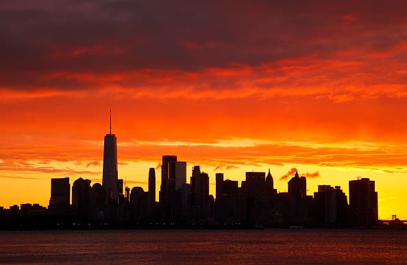 Siluetas de los rascacielos bajo las nubes, el sol ilumina a Nueva York.