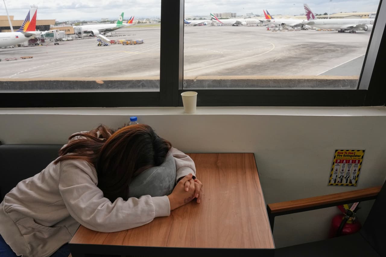 Una trabajadora filipina en el extranjero duerme mientras espera noticias de su vuelo cancelado a Oriente Medio en el aeropuerto internacional de Manila, el lunes 2 de marzo de 2026. (AP Foto/Aaron Favila)