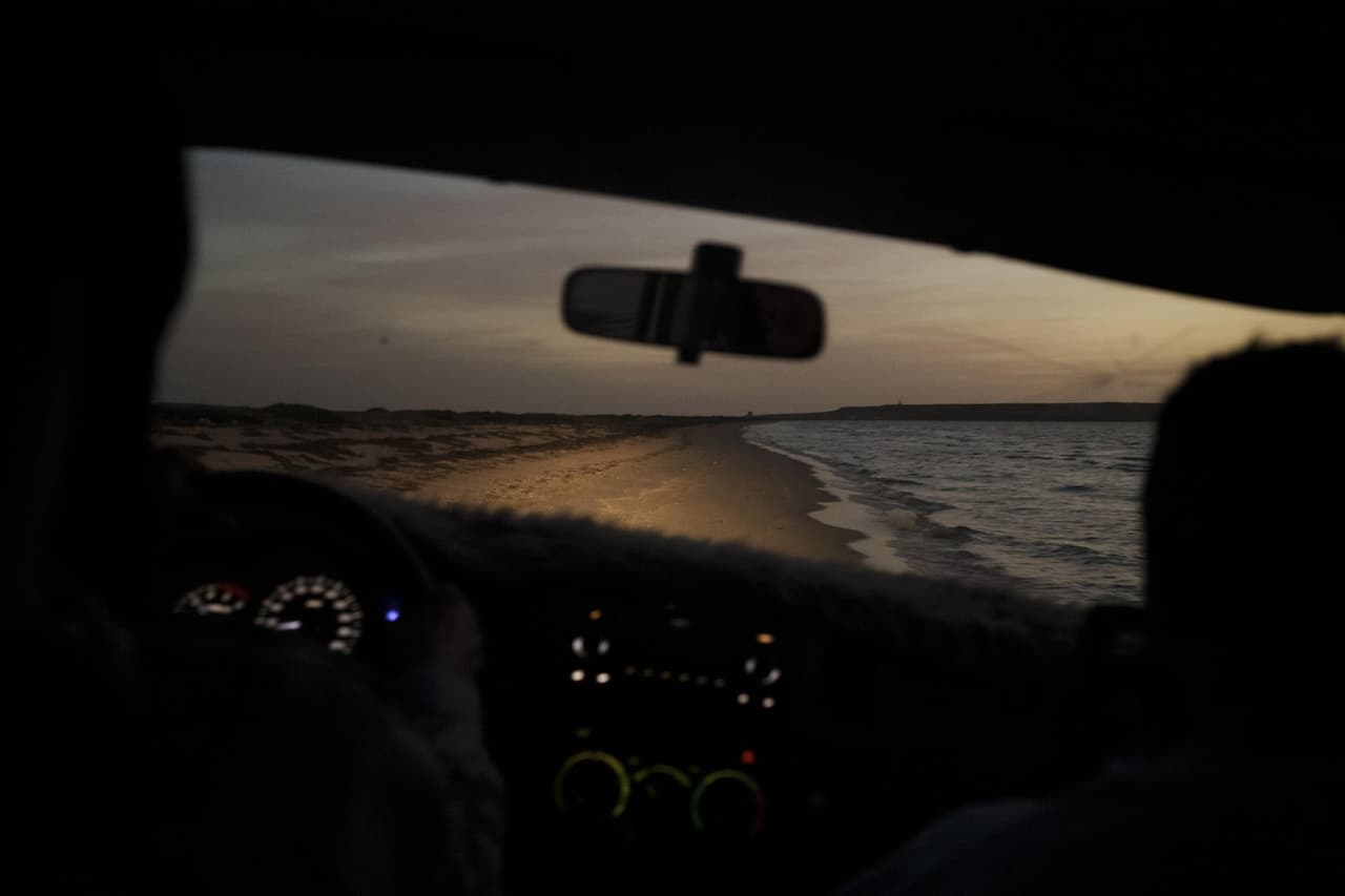 Una playa es iluminada por los faros de un auto al atardecer cerca de Nuadibú, Mauritania, el 25 de noviembre de 2021.