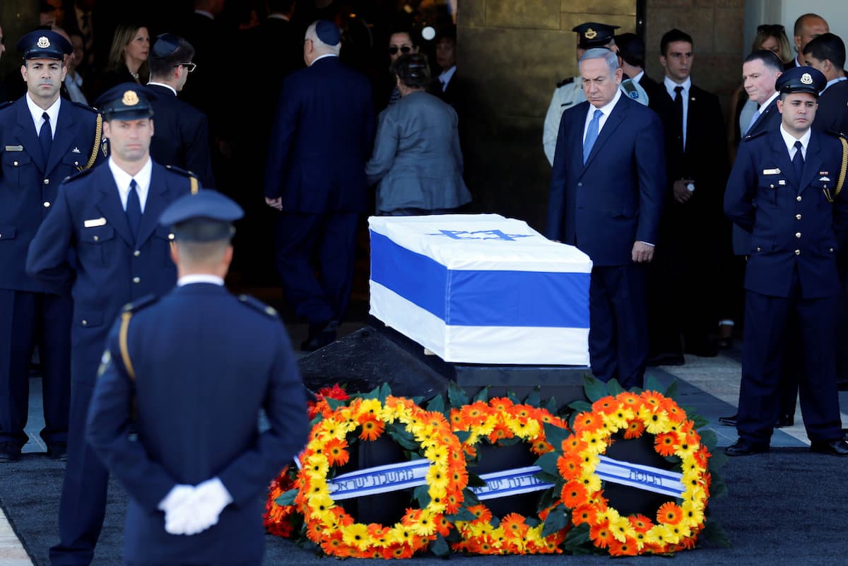El primer ministro Benjamín Netanyahu rinde honores frente al ataúd donde reposa el cuerpo de Shimon Peres, cubierto con la bandera de Israel.