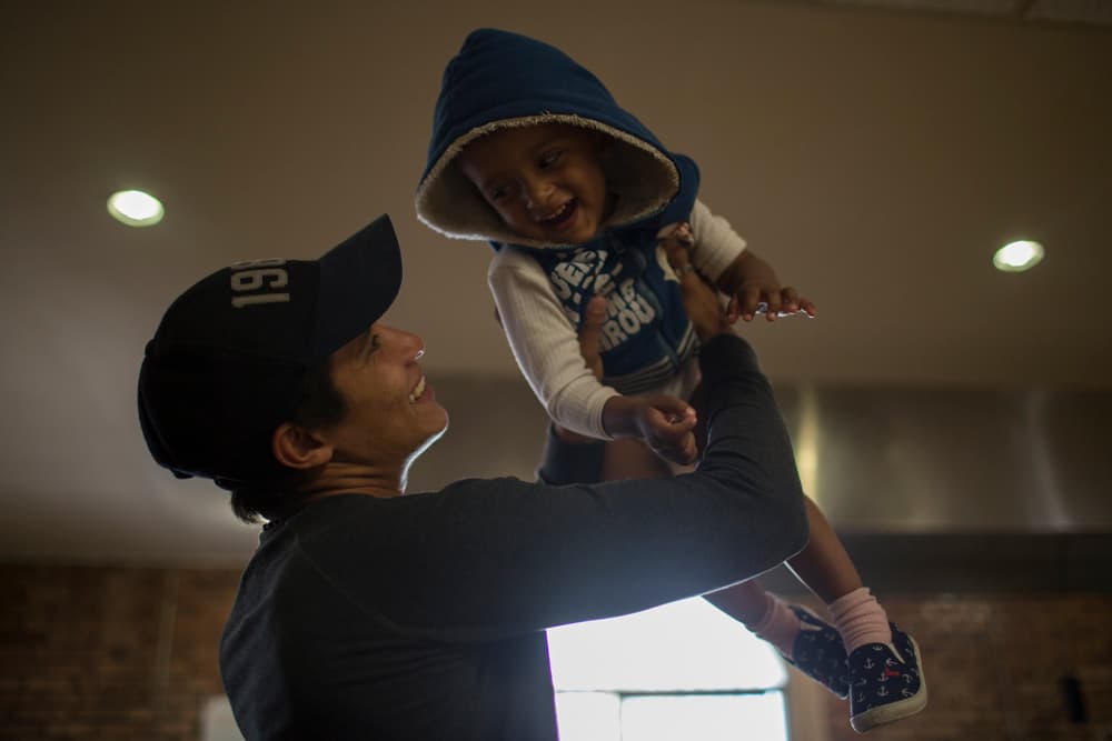Luis, de 23 años, juega con su hijo en el comedor de la Casa del Migrante, en Ciudad Juárez.
