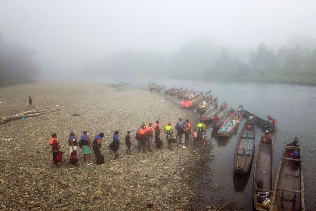 Migrantes hacen cola para ser transportados desde la aldea de Bajo Chiquito a la Estación de Recepción de Migrantes en Lajas Blancas, provincia de Darién, en Panamá, el 23 de agosto de 2021.