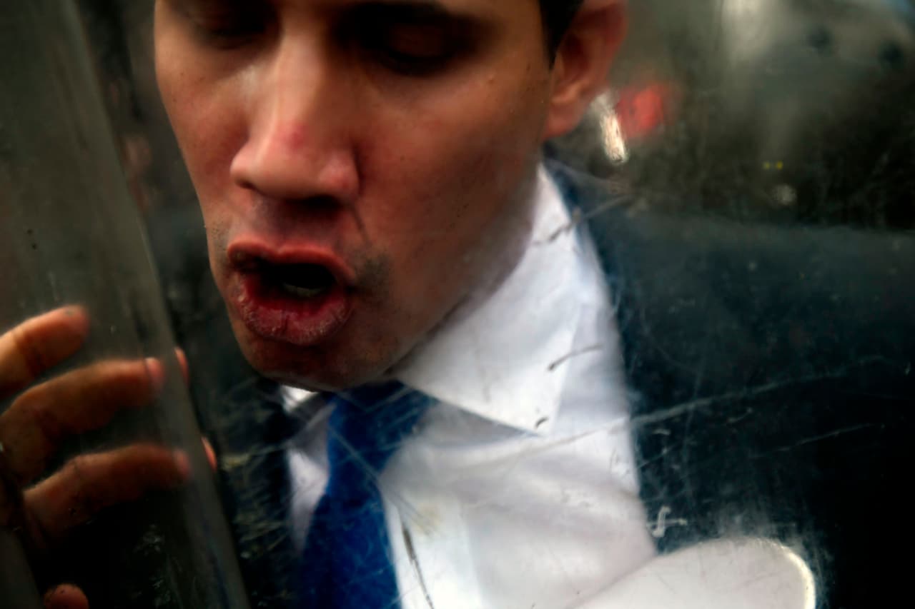 Guaidó discute a través del escudo de un funcionario antes de superar el piquete de la Guardia Nacional frente al parlamento. El dirigente, que fue reelecto el domingo por la mayoría opositora como presidente de la Asamblea Nacional, había convocado a una sesión para debatir los incidentes del fin de semana.