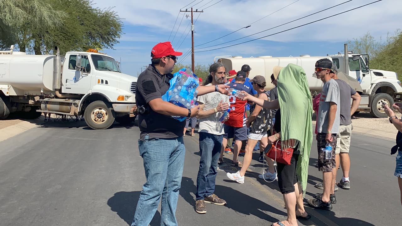 Bajo una temperatura de más de 90 grados, los organizadores regalan agua a los asistentes el evento de Trump en Tucson.