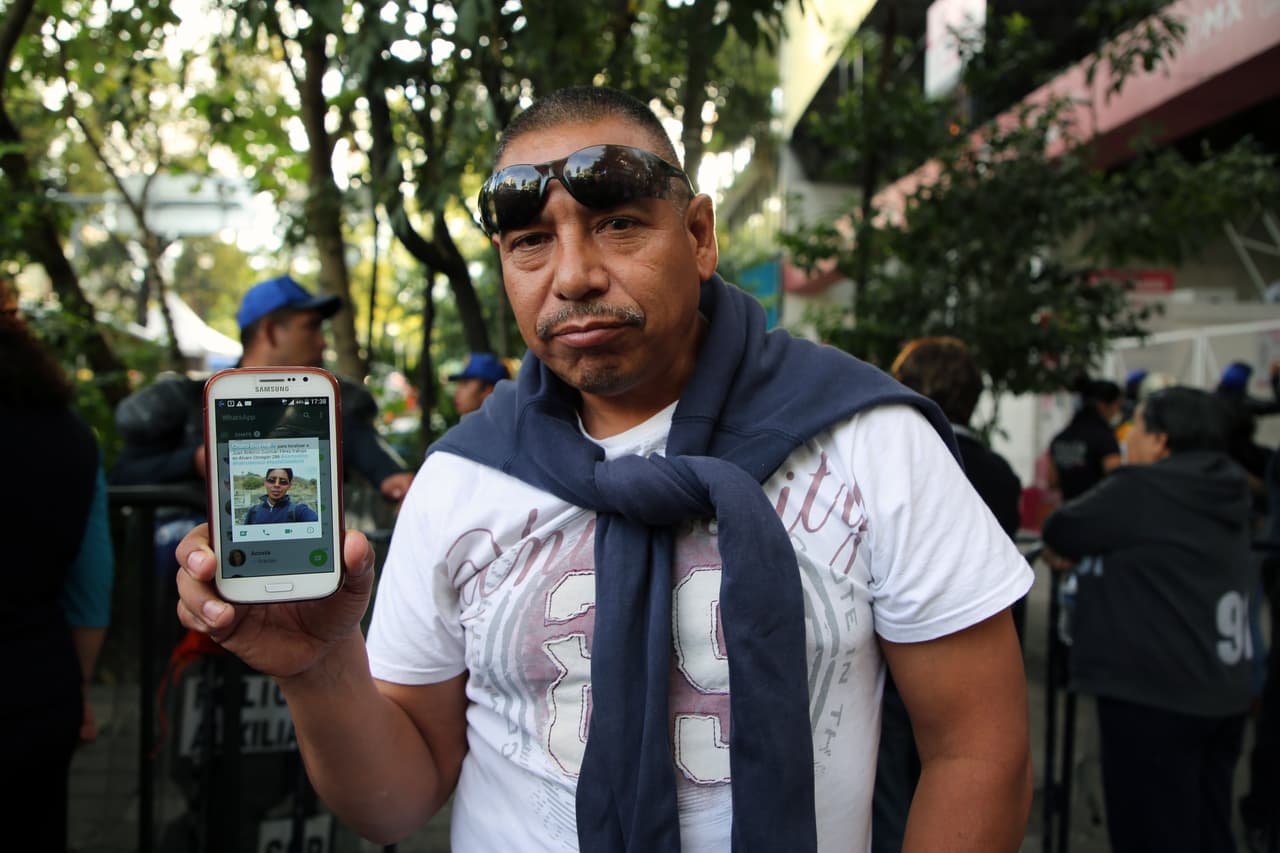 Juan Antonio Guzmán, de 45 años, trabajaba en el cuarto piso del edificio derrumbado en la avenida Álvaro Obregón y su familia está segura que se encuentra bajo los escombros. Su hermano mayor, Martín, muestra una fotografía de él.