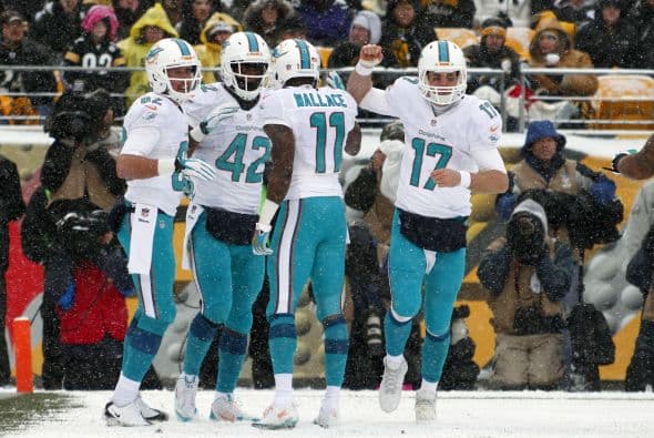 Los fanáticos de los Dolphins ya no hablan de la controversia Incognito/Martin, ni si Ireland o Philbin estarán con el equipo en el 2014, sino que pasan horas calculando… ¡porque tenemos chance de ir a los playoffs! Al principio de la temporada, y sobre todo, después de perder -casi deshonrosamente- contra Tampa Bay y Buffalo, los comentarios sobre Miami eran negativos. Qué si las novatadas, qué si Tannenhill, qué si el running game, qué si la línea ofensiva, que si… qué se yo… Pero ahora, las cosas han cambiado y solo se mencionan las posibilidades que tenemos de jugar en enero. ¡Ay, bendito! Bueno, después de este encontronazo con los portadores de las terribles toallas amarillas, donde salimos vencedores … por media pulgada… 34-28, ya todo me parece posible. Arriba Tannenhill (20 de 33, para 200 yds); arriba Wake and Odrich; arriba Thomas (105 yds, un TD en 16 acarreos); arriba Clay con sus dos TD y arriba Philbin, que mantiene el invicto en la revisión de las jugadas (obtuvo el cambio de “incomplete pass” a TD de Hartline). ¡Arriba, Dolphins, seguimos cuesta arriba!