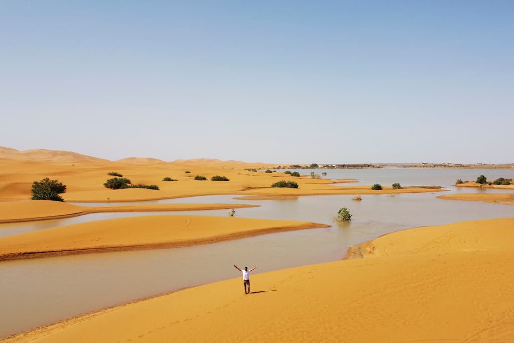 Un hombre camina sobre las dunas de arena junto a un lago provocado por las fuertes lluvias en la ciudad desértica de Merzouga, cerca de Rachidia, al sureste de Marruecos, el miércoles 2 de octubre de 2024.