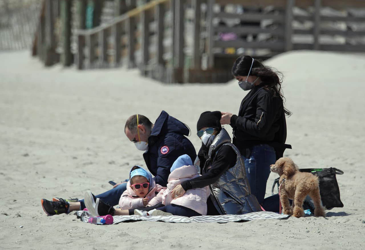 Una familia visita la playa en Long Beach, todos con mascarillas puestas, tras la nueva orden del gobernador Andrew Cuomo.