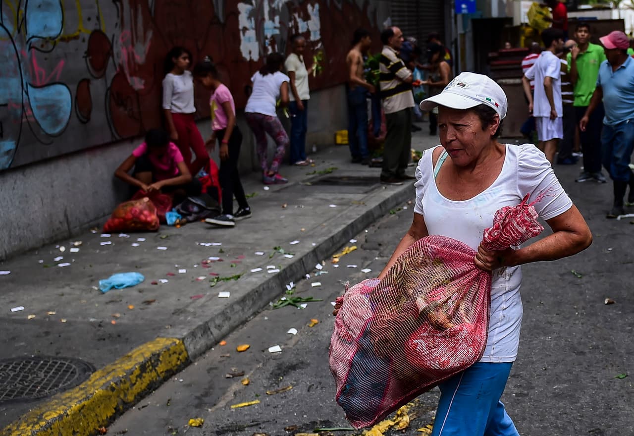 Algunos recolectaron vegetales del suelo después que un mercado callejero fue saqueado el domingo en el vecindario de Chacao, en el este de Caracas. La mayoría de los comercios están cerrados y los pocos que abren solo aceptan dinero en efectivo, incluso dólares.
