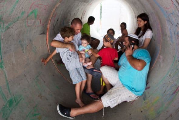 Los israelíes se esconden en un gran tubo de hormigón utilizado como refugio durante un ataque palestino con cohetes en el sur de la aldea israelí de Nitzan.