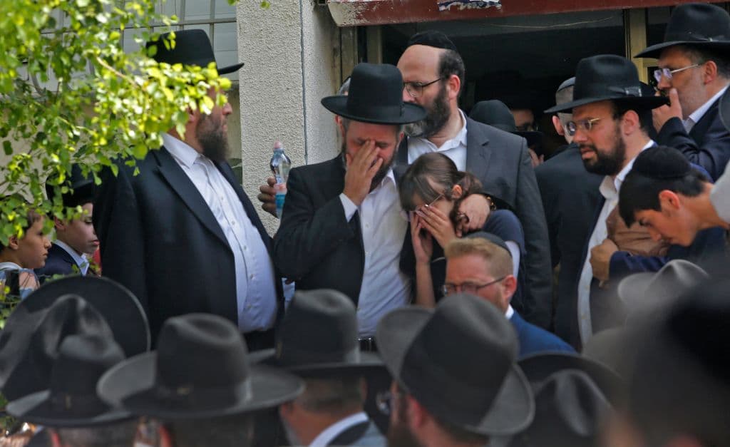 En la foto, un hombre y una mujer lloran la muerte de un ser querido en la estampida, en medio del funeral a las víctimas de esta tragedia.