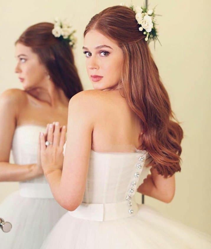 Su peinado sencillo denotó las cualidades de su cabellera peliroja, que además acompañó con una diadema de flores blancas. Marina usó un vestido corte princesa con botones plateados en la espalda que lucieron muy bien con su delgada figura.