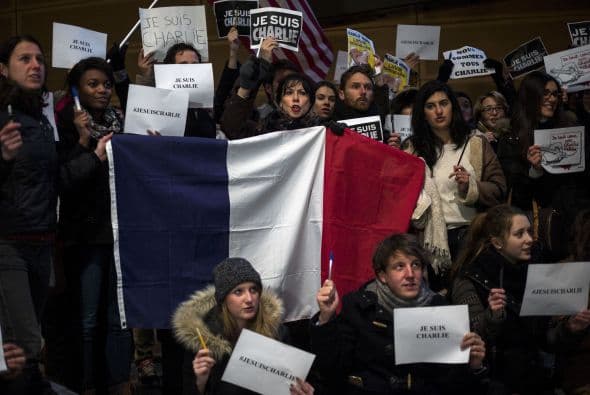 Manifestantes sostienes una bandera de Francia y mensajes de apoyo afuera de Newseum en Washington, D.C.
