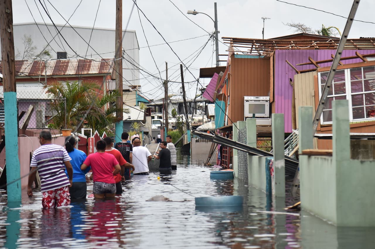 Residentes de Catano, en la provincia de Juana Matos, caminan por las aguas de la inudación.