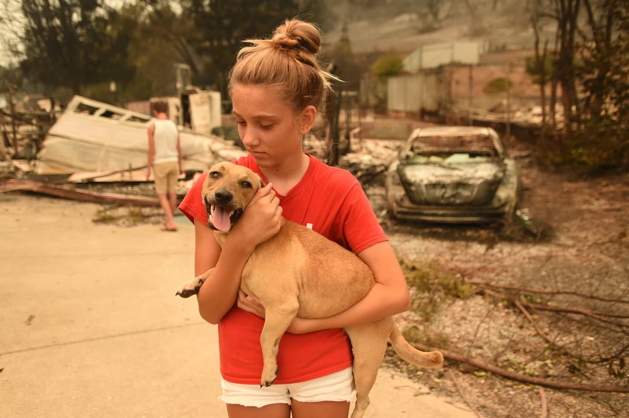 Kambryn Brilz, de 12 años, sostiene a su perrita Zoe frente a lo que queda de su hogar quemado después de que un vecino la devolviera sana y salva durante el incendio Carr en Redding, California.