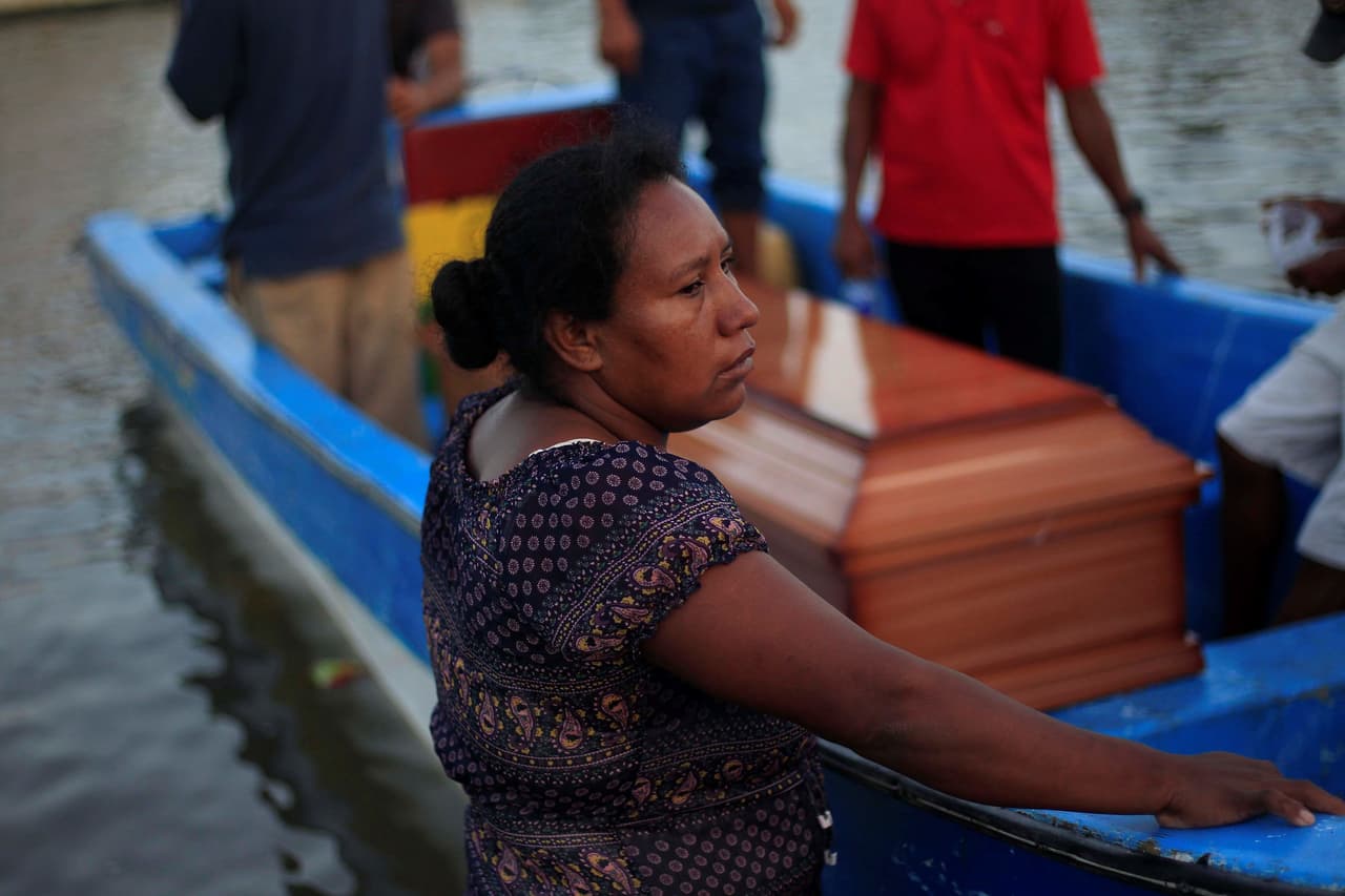 Una mujer permanece junto al féretro de un familiar que murió en un bote que se volcó este jueves, en la Base Naval de Cataratas, Puerto Lempira, en el departamento Gracias a Dios (Honduras).
