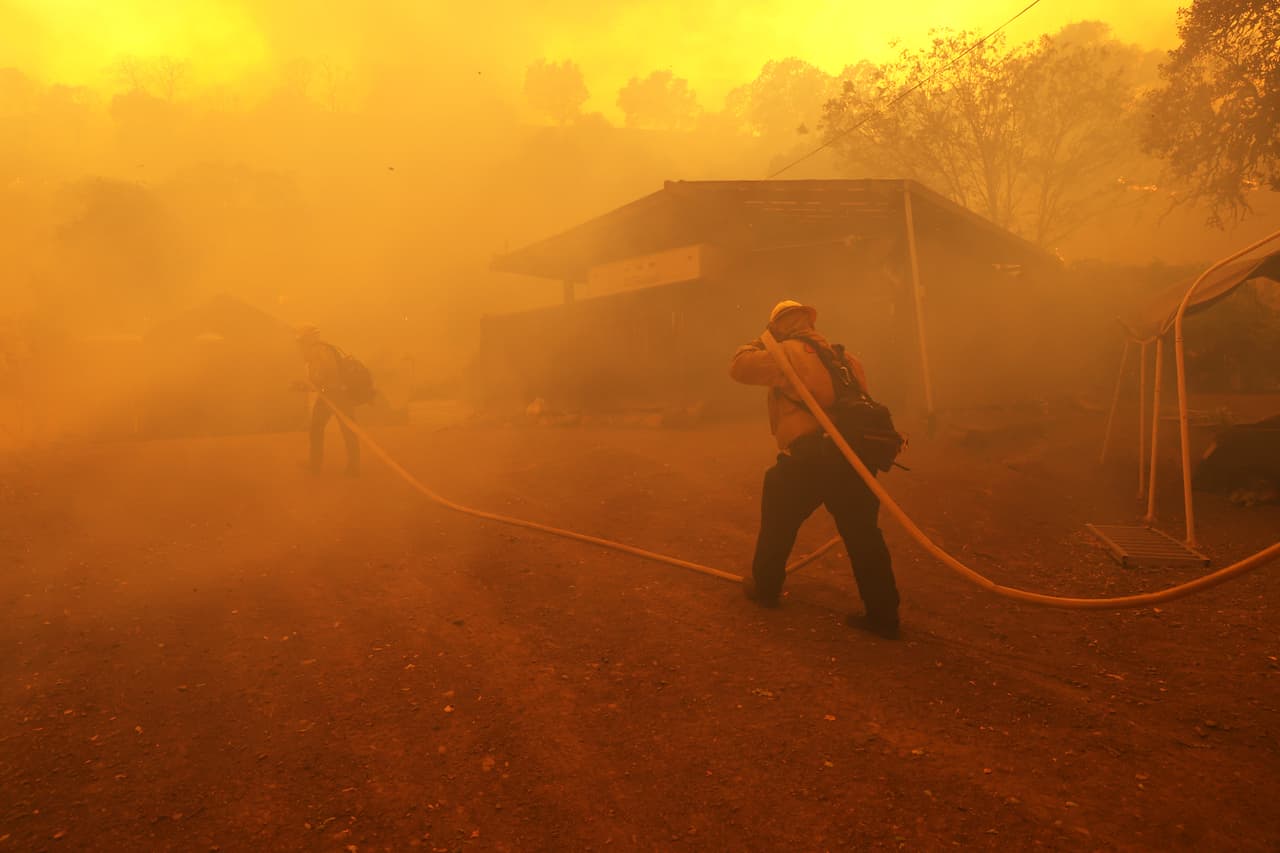 Estos bomberos cargan una manguera para acercarla al lugar del incendio en Napa.
