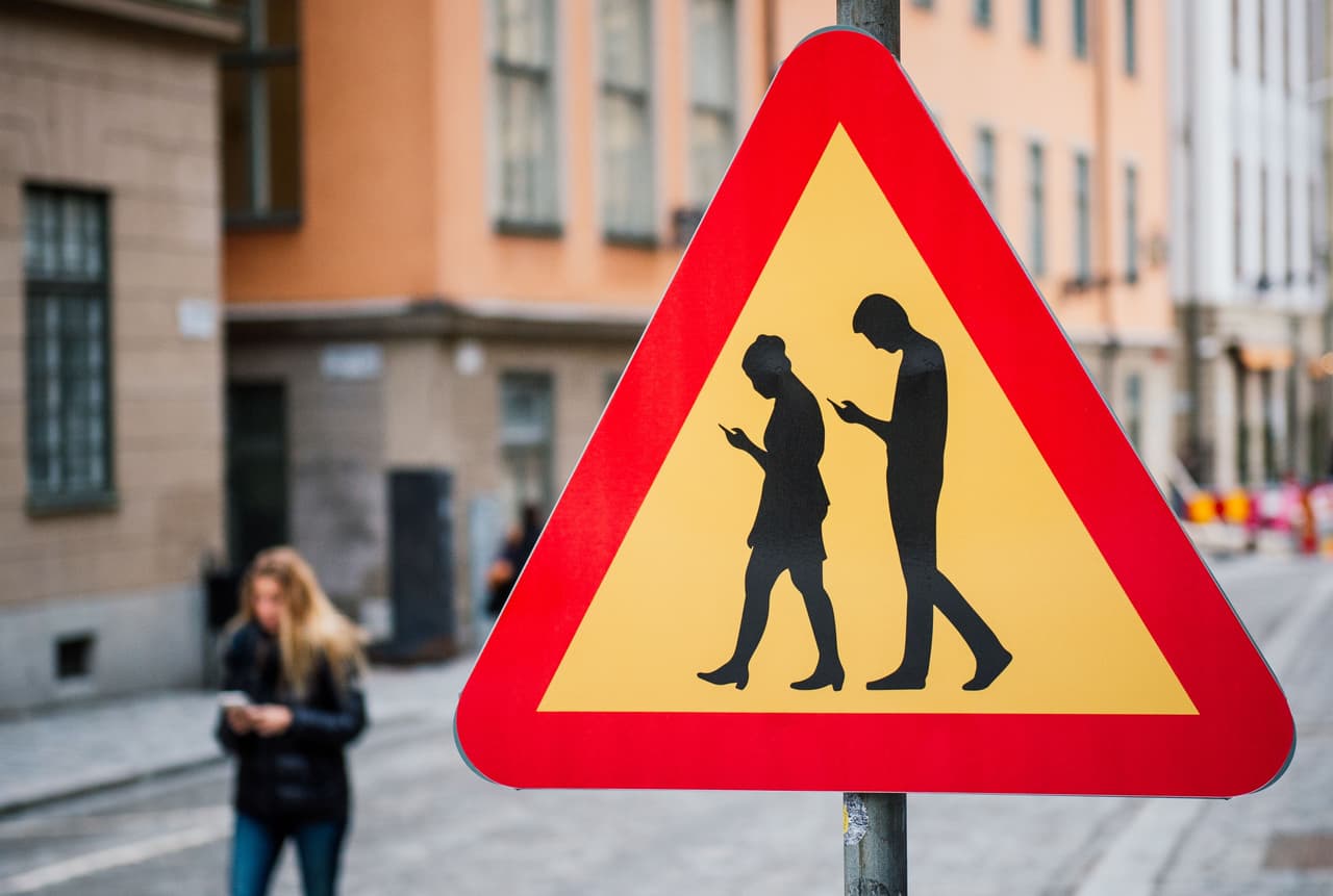 Ciudades de todo el mundo están buscando cómo enfrentar los problemas derivados de que las personas caminen distraídas en la calle por el celular. En la imagen, un cartel alerta de la presencia de personas atentas a la pantalla de sus teléfonos en Estocolmo, Suecia.