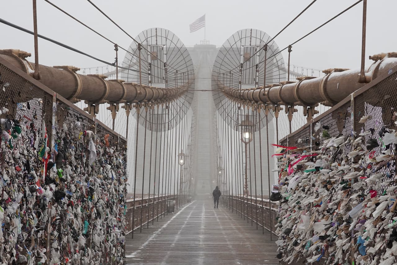 Una persona camina por el puente de Brooklyn mientras cae nieve.