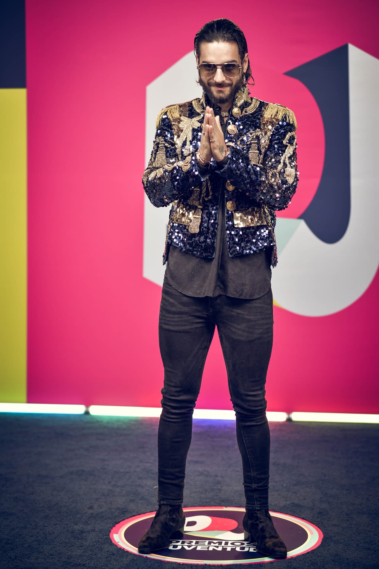 En esta ocasión optó por unos pantalones negros súper pegados, camisa oscura suelta, pelo engominado y una chaqueta cubierta de pedrería, lentejuelas, lazos y botonadoras doradas de su marca favorita.