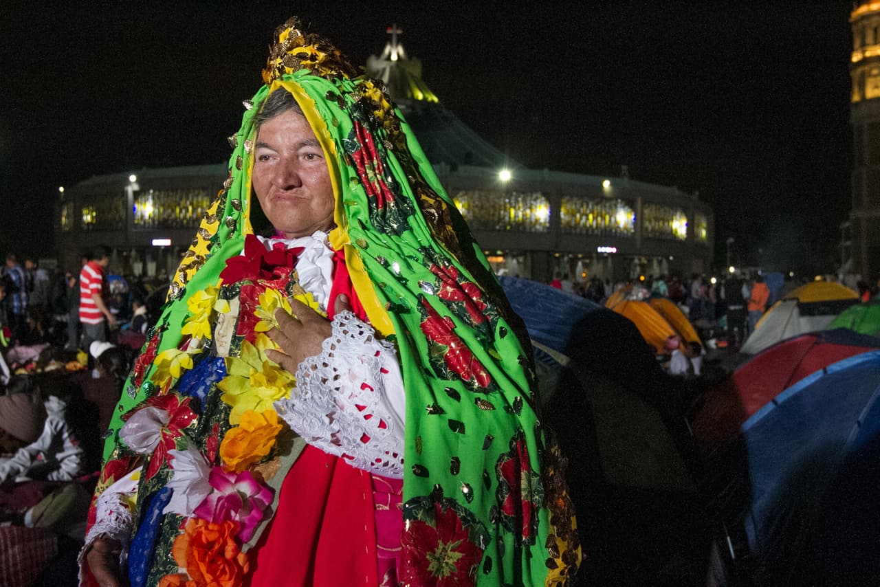 Una mujer viste un manto con bordados de la Virgen.