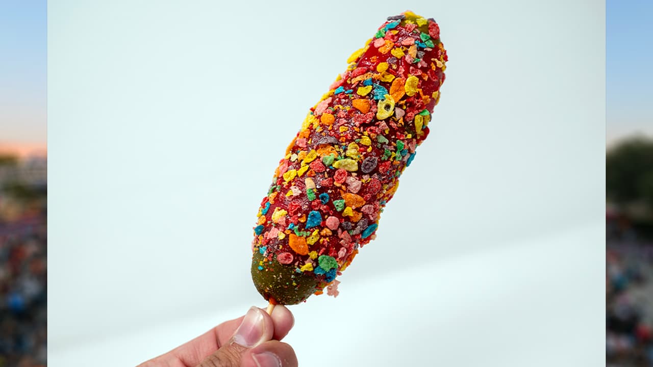 <b>THE FRUITY PEBBLE PICKLE</b> de Candy Pickle Factory
<br>
<b>Un delicioso pepinillo envuelto con Fruit Roll-Up</b>, rociado con sirope de azúcar y recubierto con cereales, además, con un toque de sirope de helado de fresa.
<b>Es crujiente, dulce y delicioso</b>.
